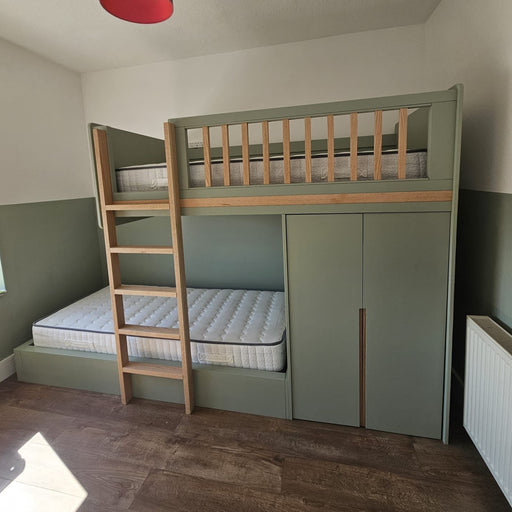 Bunk bed with green lower section and wooden ladder in a room with a red pendant light.