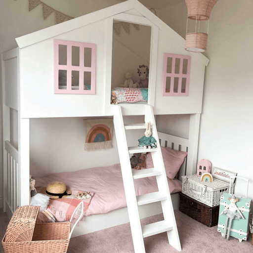A clubhouse bunk bed with white lower bed and pink upper bunk, featuring a ladder and decorative children's room setting.