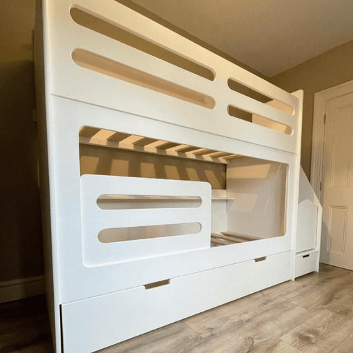 Modern white bunk bed featuring a ladder/staircase unit, a solid frame, and three large storage drawers built into the base.
