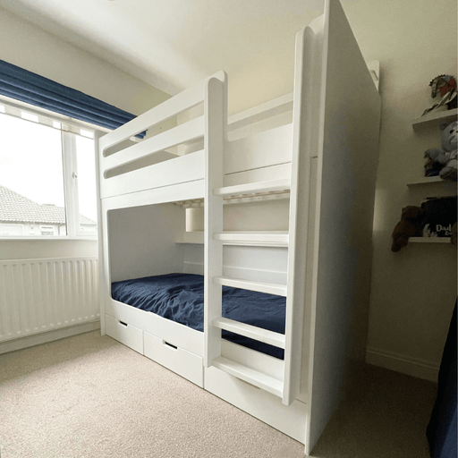 White wooden bunk bed with storage drawers and an integrated ladder in a child's bedroom.