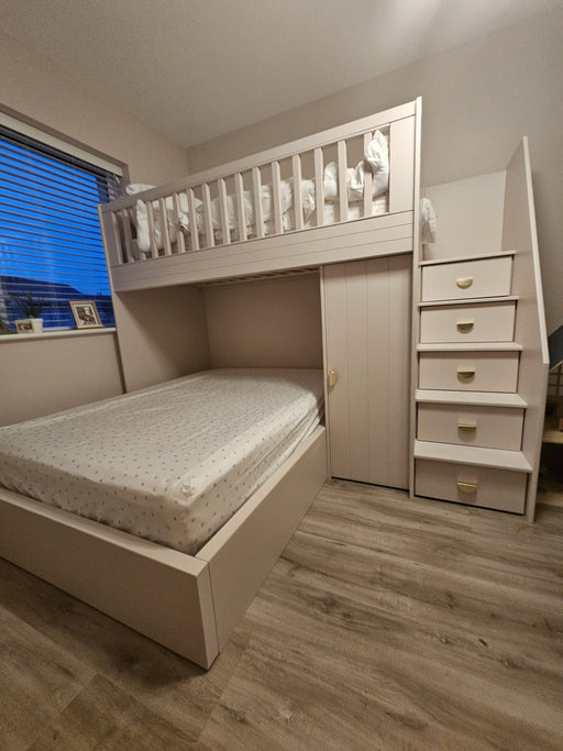 White loft bed with stairs in a room with wooden flooring and a window.