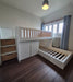White loft bed with wooden accents in a room with a radiator and window.