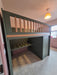 Green bunk bed with a striped desk in a room with a light fixture.