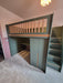 Green loft bed with stairs in a room with pink walls